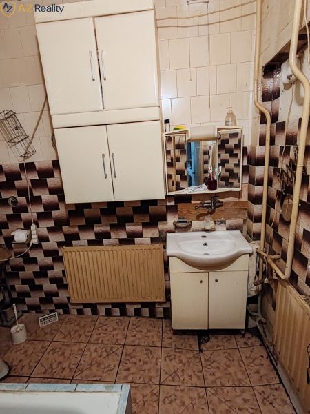 Rodinný dom na predaj Komárno - Kúpeľňa v rodinnom dome s kachličkami a umývadlovou skrinkou.