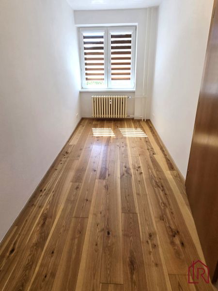 NA PRENÁJOM 4 izbový byt s loggiou, Veľký Šariš - Izba v 4-izbovom byte s veľkým oknom, podlaha s dreveným dekorom.