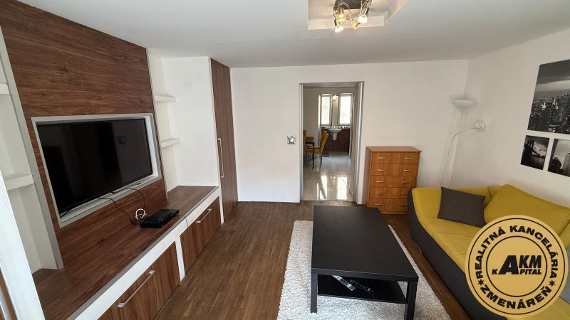 1 izbový 30m2 slnečný byt Zvolen centrum na PRENÁJOM ul. Študentská - Obývacia izba v 1-izbovom byte so sedačkou, TV a podlahou s dreveným dekorom.