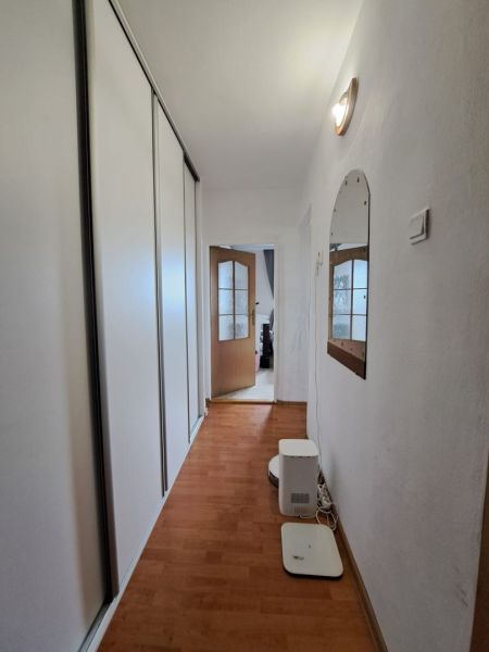 Priestranný 3-izbový byt s dvoma balkónmi na prenájom - Chodba s podlahou s dreveným dekorom v 3-izbovom byte s veľkou skriňou a zrkadlom.