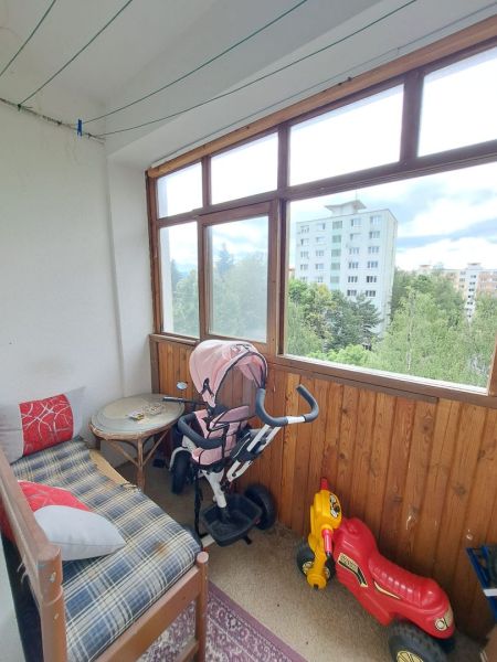 Priestranný 3-izbový byt s dvoma balkónmi na prenájom - Zasklený balkón v 3-izbovom byte s hračkami a stoličkou.