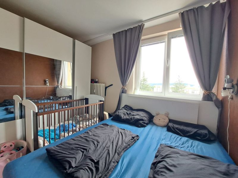 Priestranný 3-izbový byt s dvoma balkónmi na prenájom - Spálňa v 3-izbovom byte s posteľou, detskou postieľkou a veľkou skriňou.