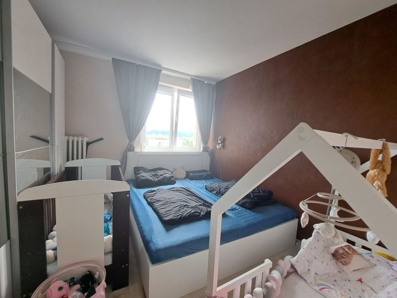 Priestranný 3-izbový byt s dvoma balkónmi na prenájom - Spálňa s detskou postieľkou v 3-izbovom byte, podlaha s dreveným dekorom.