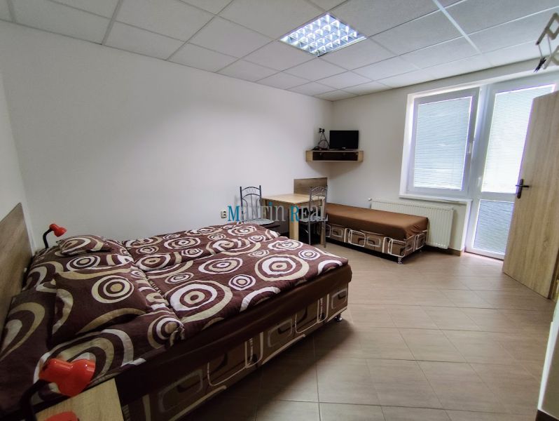 Na predaj zabehnutý ubytovací objekt – Privát - Podhájska - Svetlá spálňa s posteľou a pohovkou v rodinnom dome, podlaha s dreveným dekorom.