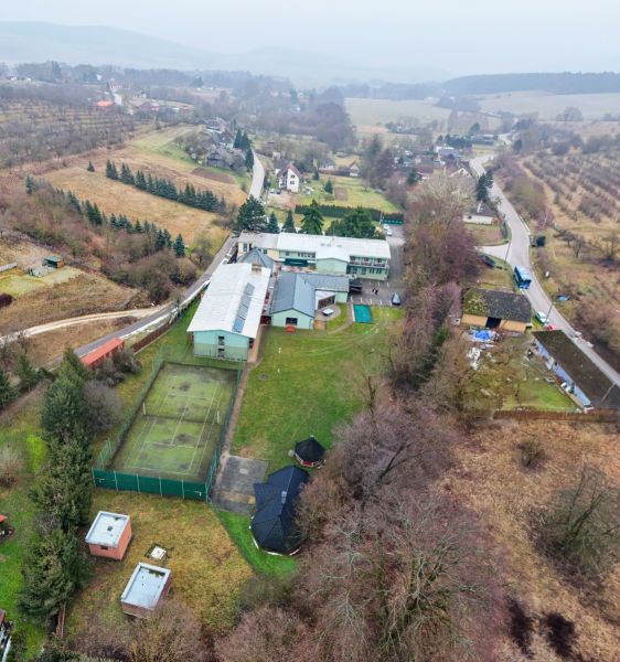 Kopanice Resort | Výnosová investícia - Letecký pohľad na Hotely a penzióny v Podkylave s tenisovým kurtom a zelenými plochami.