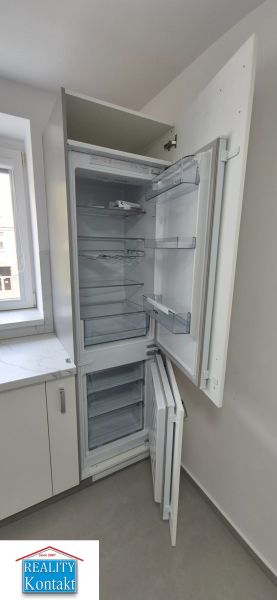 Na prenájom kompletne prerob. NOVÝ 2 izbový byt čiast.zar. Nové Zámky - V 2-izbovom byte je kuchyňa s chladničkou a bielymi skrinkami.