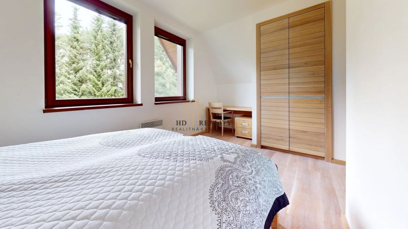 Pripravujeme do ponuky jedinečný apartmánový bytový dom Donovaly  - Spálňa v Chate s podlahou s dreveným dekorom, posteľou a výhľadom na stromy.