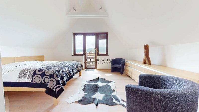 Pripravujeme do ponuky jedinečný apartmánový bytový dom Donovaly  - Svetlá spálňa v chate s dekorom dreva, posteľou a kreslom.