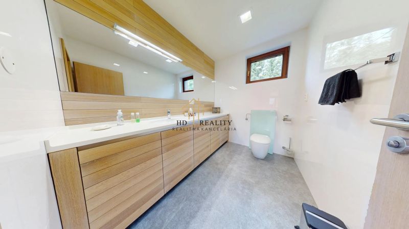 Pripravujeme do ponuky jedinečný apartmánový bytový dom Donovaly  - Moderná kúpeľňa v chate so svetlým drevom a veľkým zrkadlom.