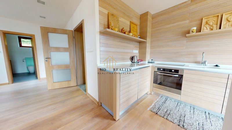 Pripravujeme do ponuky jedinečný apartmánový bytový dom Donovaly  - Interiér chaty s kuchyňou, dreveným dekorom a vstupom do kúpeľne.
