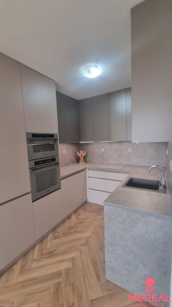 2-izbový moderný byt, s garážovým státím  novostavba, Coboriho ulica - Kuchyňa v 2-izbovom byte s podlahou s dreveným dekorom a vstavanými spotrebičmi.