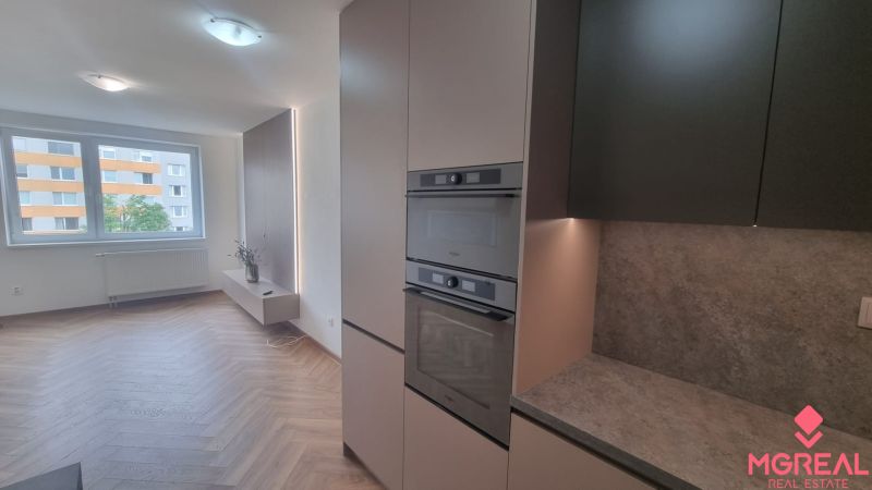 2-izbový moderný byt, s garážovým státím  novostavba, Coboriho ulica - Kuchyňa v 2-izbovom byte s podlahou s dreveným dekorom a zabudovanými spotrebičmi.