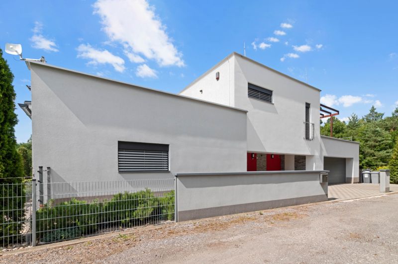 ARCHITEKTÚRA TICHA A MODERNÝCH TECHNOLÓGIÍ - SMART VILLA V OBJATÍ LESA - Rodinný dom na Záhradnej ulici v Lukavici s modernou fasádou a garážou.