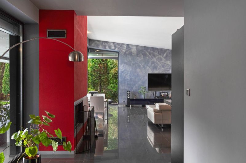 ARCHITEKTÚRA TICHA A MODERNÝCH TECHNOLÓGIÍ - SMART VILLA V OBJATÍ LESA - Interiér rodinného domu s červenou stenou, televízorom a moderným sedením na podlahe s dekorom.