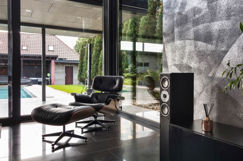 ARCHITEKTÚRA TICHA A MODERNÝCH TECHNOLÓGIÍ - SMART VILLA V OBJATÍ LESA - Kožené kreslo a reproduktor v Rodinnom dome s výhľadom na exteriér.