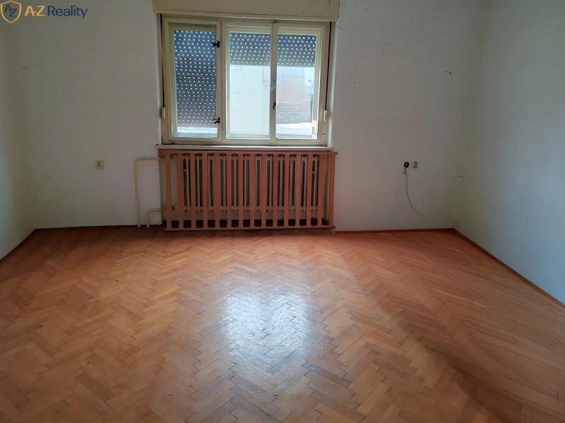 Ponúkame Rodinný dom vhodný na bývanie aj podnikanie - Prázdna izba v Rodinnom dome s podlahou s dreveným dekorom a dreveným radiátorom.