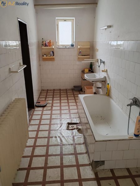 Ponúkame Rodinný dom vhodný na bývanie aj podnikanie - Kúpeľňa v rodinnom dome s vaňou, umývadlom a oknom. Biele kachličky a dlažba.