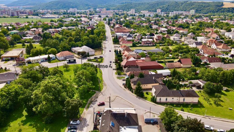 Útulný penzión s reštauráciou na PREDAJ - Letecký pohľad na Hlavnú ulicu, obklopenú zeleňou a gastro priestormi v pozadí.