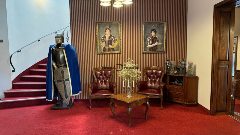 NA PREDAJ hotel s reštauráciou - Brnenie a stredoveké dekorácie na červenom koberci v interiéri penziónu.