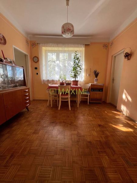 Rodinný dom v Záhorskej Bystrici na ulici Donská - Izba v rodinnom dome s podlahou s dreveným dekorom, jedálenským stolom a vitrínou.