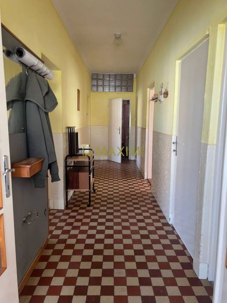 Rodinný dom v Záhorskej Bystrici na ulici Donská - Kachličková podlaha, žlté steny a kabát na vešiaku v chodbe rodinného domu.