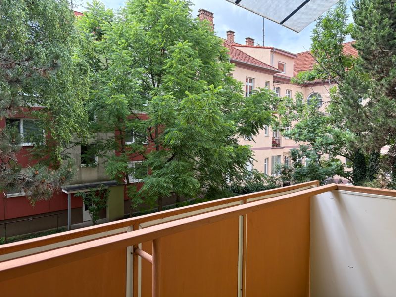 Ponúkame na predaj veľký 2 i byt v Nových Zámkoch, ul. Šafárikova ! - Balkón v 2-izbovom byte na Šafárikovej ulici v Nových Zámkoch, obklopený zeleňou a budovami.