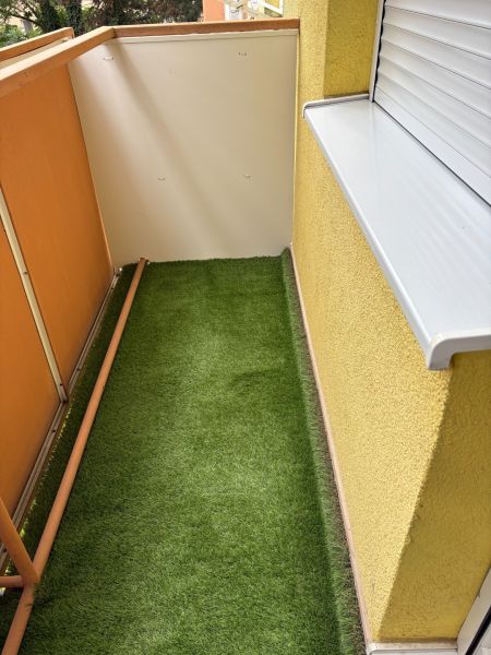 Ponúkame na predaj veľký 2 i byt v Nových Zámkoch, ul. Šafárikova ! - Balkón 2-izbového bytu na Šafárikovej ulici v Nových Zámkoch, podlaha s umelou trávou.