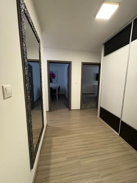 Ponúkame na predaj veľký 2 i byt v Nových Zámkoch, ul. Šafárikova ! - Chodba v 2-izbovom byte s podlahou s dreveným dekorom a zrkadlom na stene.