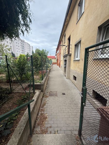 2-izbový byt s vlastnou záhradkou,plynovým kotlom, špajzou  - Ulica Námestie Jozefa Emanuela vo Vrbovom vedľa 2-izbového bytu, obklopená vegetáciou.