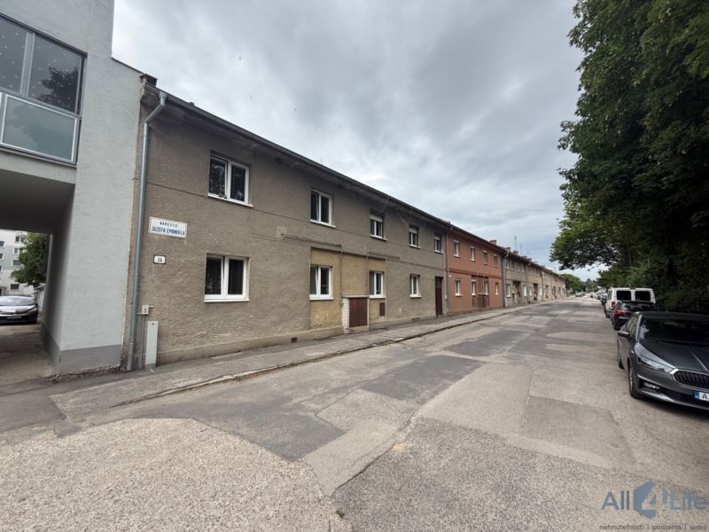 2-izbový byt s vlastnou záhradkou,plynovým kotlom, špajzou  - Ulica Námestie Jozefa Emanuela vo Vrbovom, radové domy a autá na ceste.