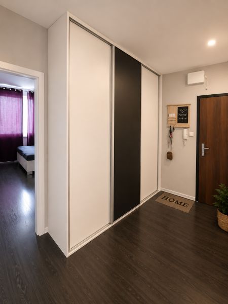 REZERVOVANÝ - Na predaj priestranný 2-izbový byt s balkónom, klímou... - Interiér 2-izbového bytu s chodbou a vstavanou skriňou, podlaha s dreveným dekorom.