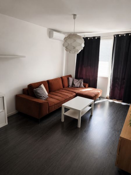 REZERVOVANÝ - Na predaj priestranný 2-izbový byt s balkónom, klímou... - Obývacia izba s tmavou podlahou s dreveným dekorom, sedačkou a konferenčným stolíkom v 2-izbovom byte.