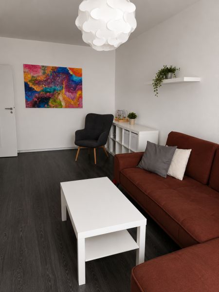 REZERVOVANÝ - Na predaj priestranný 2-izbový byt s balkónom, klímou... - Obývacia izba v 2-izbovom byte s tmavou podlahou a svetlým nábytkom.