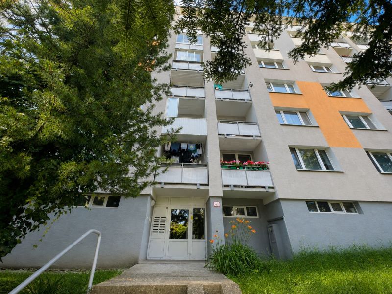 Na prenájom 3 izbový byt - Banská Bystrica, Starohorská ulica - Bytový dom na ulici Starohorská v Banskej Bystrici, obklopený zeleňou a kvetmi.