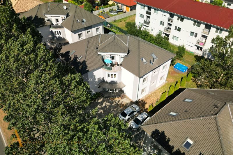 Na predaj 3-izb. byt s balkónom v novost., Vrakúň - Strecha a dvor pri 3-izbových bytoch vo Vrakúni s okolitými stromami a autami.