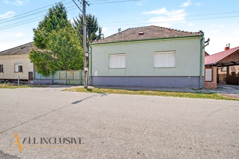 Na predaj 5-izb.rd vhodný na dvojgen. býv., Topoľníky - Rodinný dom v Topoľníkoch so zeleným plotom a škridlovou strechou.