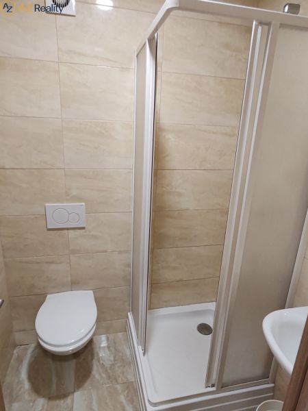 Na prenájom 3  izbový byt v Komárne - Kúpeľňa s toaletou, sprchovacím kútom a béžovými obkladmi v 3-izbovom byte.