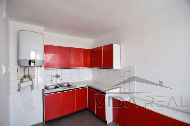 Priestranný 3-izbový byt | 72 m² + 9 m² loggia + 9 m² pivnica |  - Červená kuchyňa v 3-izbovom byte s bielymi obkladačkami a umývadlom.