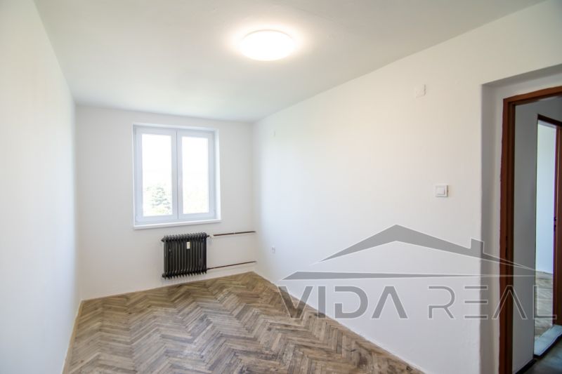 Priestranný 3-izbový byt | 72 m² + 9 m² loggia + 9 m² pivnica |  - Izba v 3-izbovom byte s podlahou s dreveným dekorom a oknom.