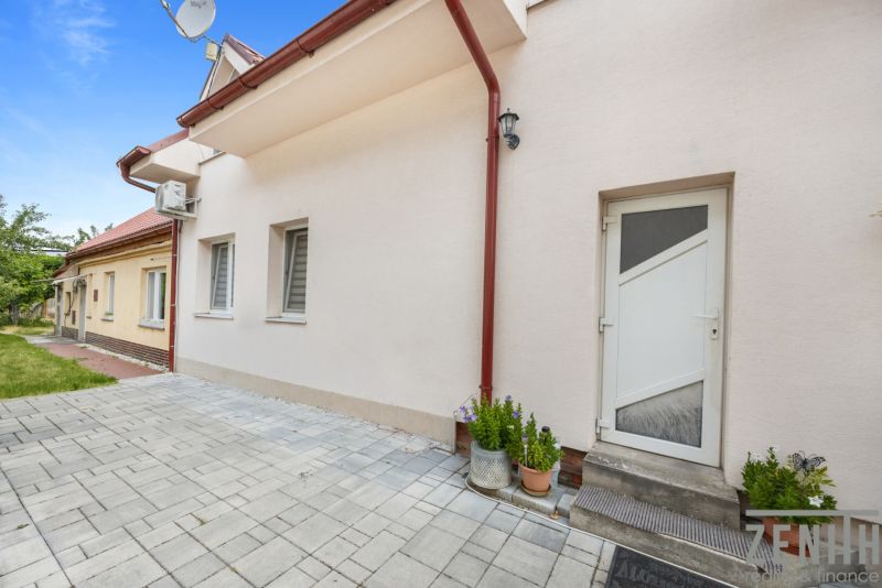 VAJNORY Bratislava -  Rodinný dom s veľkym potenciálom na predaj  - Rodinný dom na Roľníckej ulici, Bratislava - Vajnory, má dláždený dvor a bielu fasádu.