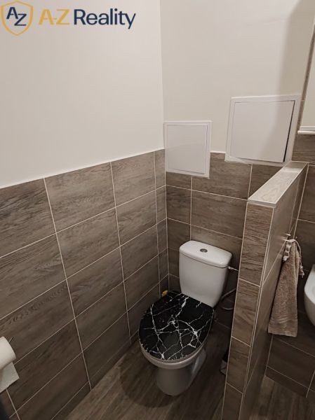 Pekný 1 izbový byt s balkónom na prenájom - Kúpeľňa v 1-izbovom byte s obkladmi, toaletou a podlahou s dreveným dekorom.