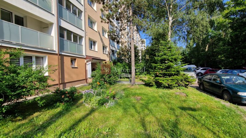 AstonReal: na predaj 2-izbový byt 54 m2 - Poprad, Komenského - Exteriér bytového domu na Komenského ulici v Poprade s parkoviskom a zeleňou.