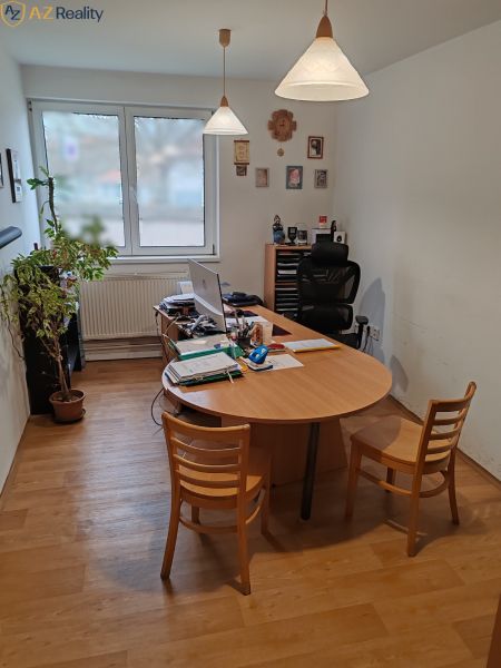 Komerčný objekt na predaj  v Komárne - Kancelária s dreveným stolom a podlahou s dreveným dekorom, osvetlená závesnými lampami.