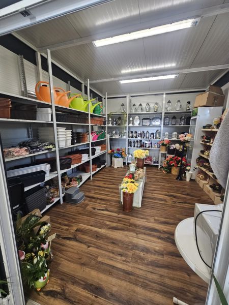 NA PREDAJ *** PREVÁDZKA  70M2 PRI HLAVNEJ CESTE V BERNOLÁKOVE *** - Interiér obchodných priestorov s regálmi plnými kvetináčov, svietnikov a umelých kvetov.