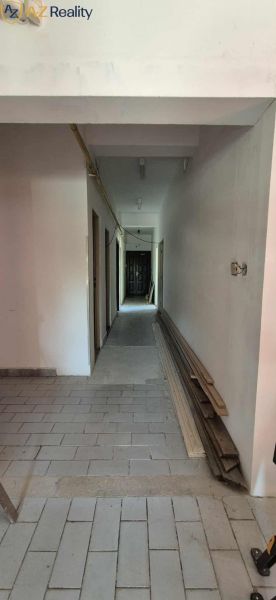 Komerčný objekt na predaj v Chotíne - Chodba v budove Komárna s dlažbou a hromadou stavebného materiálu.