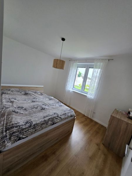 Predaj 4 izbového rodinného domu, pozemok od 523 m2,  NOVOSTAVBA 2023 - Spálňa v rodinnom dome s posteľou, podlahou s dreveným dekorom a svetlým závesom.