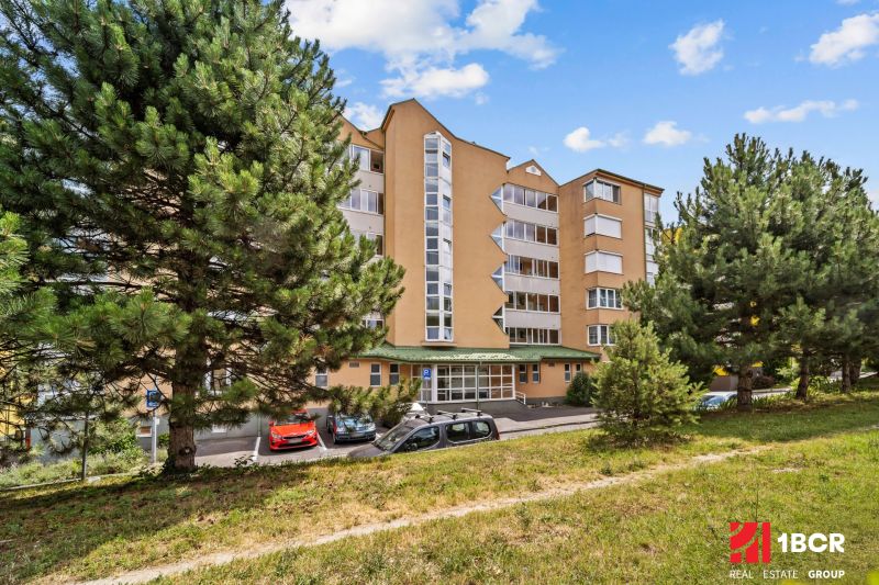 1.BCR | SVETLÝ 1,5-IZBOVÝ BYT S MOŽNOSŤOU ÚPRAVY NA 2-IZBOVÝ - LAMAČ  - Bytový dom na Heyrovského ulici, Bratislava - Lamač, obklopený stromami a zeleňou.