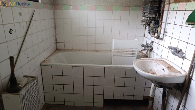 Na predaj starší rodinný dom s podkrovím v obci Gbelce - Kúpeľňa v rodinnom dome s vaňou a umývadlom so zanedbanými obkladmi.