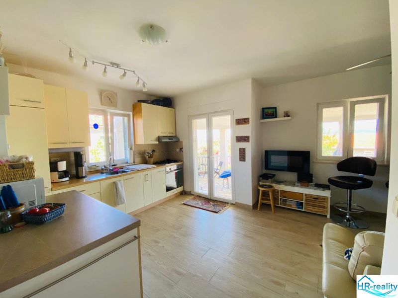 Brač(HR)- zariadený apartmán s výhľadom na more - Kuchyňa a obývačka s podlahou s dreveným dekorom v rekreačnom apartmáne.