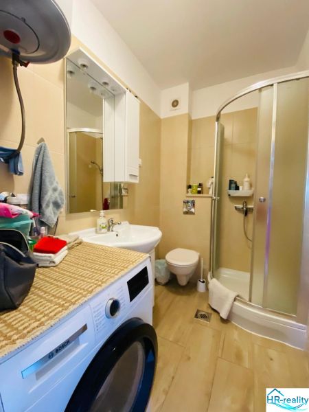 Brač(HR)- zariadený apartmán s výhľadom na more - Kúpeľňa s práčkou, sprchovacím kútom a podlahou s dreveným dekorom v rekreačnom apartmáne.